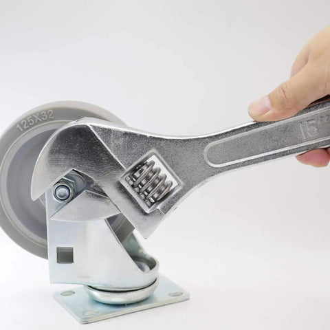 Hand using 15 Inch Adjustable Wrench With 45mm Jaw Opening For Heavy Duty Garage And DIY Projects on a large caster wheel