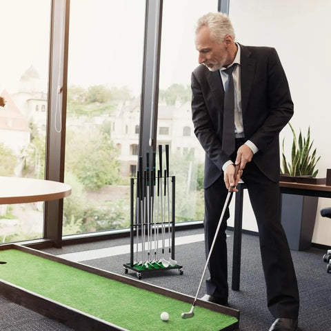 Man using office putting green with Sturdy Ten Club Golf Storage Rack Stand For Garage And Home Golf Simulator Holds Ten Clubs