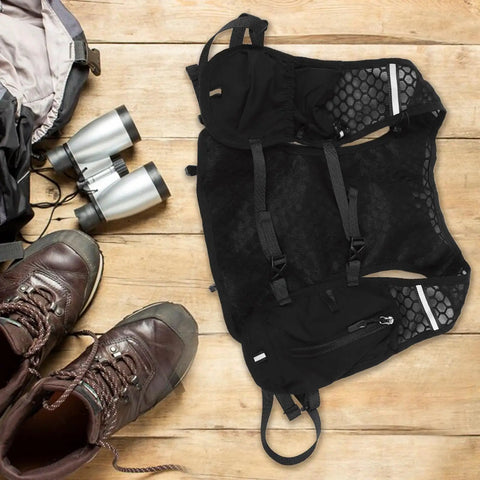 Go To Hydration Backpack for Running Cycling and Hiking with Quick Access Water Bladder on wooden floor with hiking boots