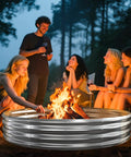 Group enjoying campfire in Big 6 Foot Metal Fire Pit Ring; silver steel, 0.7mm thick, 1 foot high, perfect for outdoor gatherings.