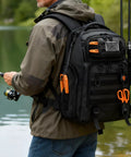 Person fishing by a lake wearing 50L Fishing Tackle Backpack With Removable Lure Wraps, Four Clear View Tackle Boxes, Two Rod Holders.