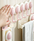 Heavy Duty Six Hook Adhesive Wall Rack With Smooth 180 Degree Swivel And Easy No Drill Mount holding towels in pink color on a wall.