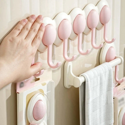 Heavy Duty Six Hook Adhesive Wall Rack With Smooth 180 Degree Swivel And Easy No Drill Mount holding towels in pink color on a wall.