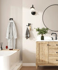 Super Slick Swivel Towel Hook With Three Turning Arms Matte Black Wall Mount Coat Rack holding a robe and towel in a stylish bathroom.