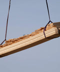Side view of a bundle of light wooden planks strapped with purple lifting slings