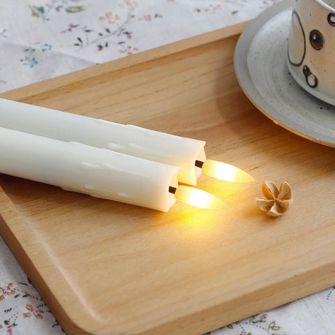Two ivory flameless LED candles on a tray, part of Six Pack 7.5 Inch Ivory Flameless LED Taper Candles With Remote And Two Remote Controls Battery Operated Window Candles Timed Set Of 6 With Realistic 3D Wax Drip Look Plastic 0.86 Inch Diameter Warm Flicker Ambiance.