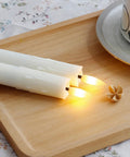Two ivory LED candles on a wooden tray, part of Eight Pack Flameless Flickering Taper Candles With Remote Control, 7.5 Inch Ivory LED Window Candles.
