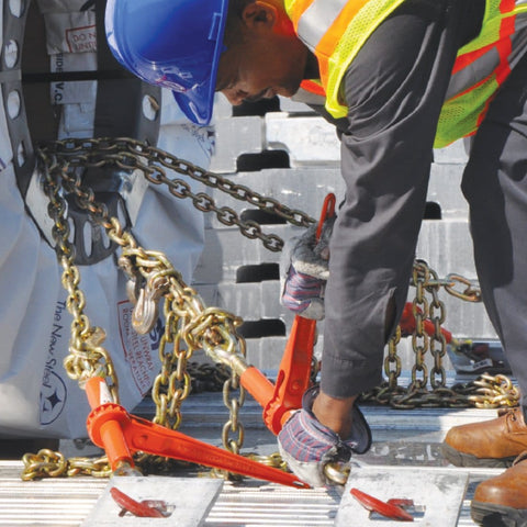 Worker using Beefy Ratchet Style Load Binder With Two Grab Hooks 7100 Lb Safe Working Load Fits 5/16 Or 3/8 Inch Grade 70 And Grade 80 Chain Forged Steel Pawl And Gear For Safe, Easy Tie Down on trailer