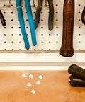 White Plastic Hole Plugs Set With Locking Screw Caps For Furniture And Office Installations on a workbench with tools in background.