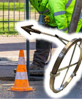Worker using Tough As Nails 50 Ft Manganese Steel Sewer Snake Cable for unclogging sewer lines near a safety cone.
