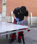 Man using a grinder on a heavy duty adjustable tile table for large format ceramic sheets, extending 43 to 59 inches.