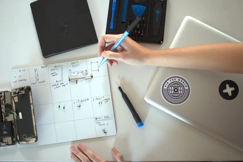 Person using a Slick Magnetic Project Mat With Rewritable Surface For Super Tight Electronics Organization Keep Screws And Parts Sorted In Twenty Zones While You Fix Iphones And Macs Solid Setup.