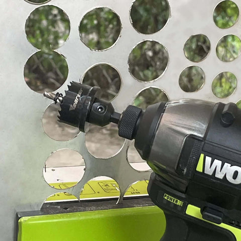 WORX cordless drill with metal bi-metal hole saw attachment cutting circular holes in perforated metal panel.