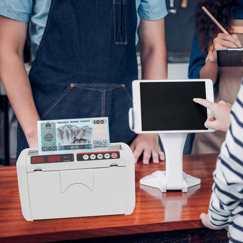 Portable Rechargeable Cash Counting Machine With UV And MG Counterfeit Detection in use on a wooden counter in a shop setting.
