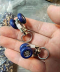 Heavy Duty Silent Curtain Track Gliders 20 Piece Pack with blue metal pulleys shown in hand for ceiling or window use.