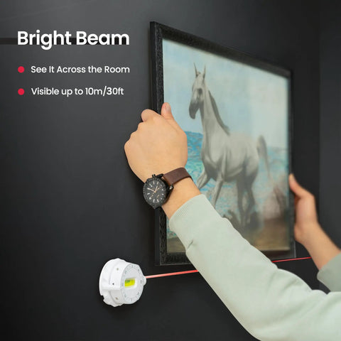 Person using Multi Surface Laser Level With Wall Mount And Pins Or Sticky Pads to align picture on wall with precision.