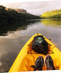 View from a kayak on a peaceful lake with lush green hills, featuring heavy duty kayak roof rack straps with quick buckles.