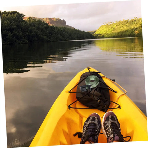 View from a kayak on a peaceful lake with lush green hills, featuring heavy duty kayak roof rack straps with quick buckles.