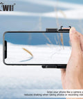 Compact Phone Camera Grip Handle With Tripod Mount Remote Shutter shown gripping a smartphone in snowy landscape for steady video shooting.