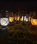 Bronze Outdoor LED Lantern With Vintage Flame Effect for garden and patio decor, multiple lanterns lit on grass.