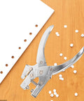 Handheld Metal Hole Puncher For Office And Crafts Single Hole Paper Punch on wooden surface with punched paper confetti