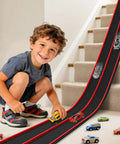 Child playing on stairs with Hot Wheels Compatible 15 Ft Flexible Race Track Starter Set With Sturdy Suction Cups Rolls Up Portable Wall Ramp And Spiral Track For 1 64th Scale Diecast Cars Kid Friendly Red And Black.