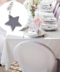 Eight Ounce Tablecloth Weights with Stainless Steel Clips for Outdoor Tables shown clipped to white cloth in bright setting, gray star detail