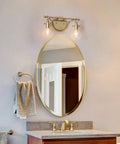 Two Light Gold Vanity Light With Clear Glass Shades For Bathroom above a mirror in soft gold finish, 14x4.5x8 inches