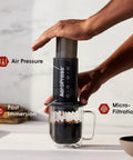Person using Barista Level Portable Coffee Maker With Chamber And Plunger And Filters For Espresso Style Brews On The Go Quick Coffee Machine