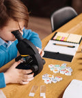 Boy using microscope with Science Mini Erasers 80 Pack With Eight Pattern Erasers Microscope U Shaped Magnets DNA on table.