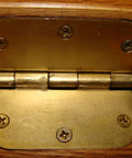Close-up of a brass hinge on a wooden door being lubricated with Green Wonder 300 Ml Plant Based Aerosol Cleaner And Lubricant For Doors Locks Hinges Chains And Valves, Cleans And Lubricates While Wiping Out Grease Rust Ink Permanent Markers Nail Polish And Labels, No Mess Eco Friendly Biodegradable Formula