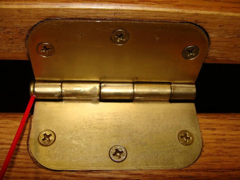 Close-up of a brass hinge on a wooden door being lubricated with Green Wonder 300 Ml Plant Based Aerosol Cleaner And Lubricant For Doors Locks Hinges Chains And Valves, Cleans And Lubricates While Wiping Out Grease Rust Ink Permanent Markers Nail Polish And Labels, No Mess Eco Friendly Biodegradable Formula