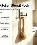 Rock Solid Self Adhesive Wall Hooks Crafted From Premium Stainless Steel For Zero Drill Wall Mounting And Effortless Home Organization With A Smooth Silver Look Set Of Four holding a brush in a kitchen.