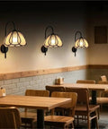 Nordic Floral Petal Wall Sconce Fabric Shade Wall Light,Warmth in a cozy cafe setting with three soft-lit wall sconces.