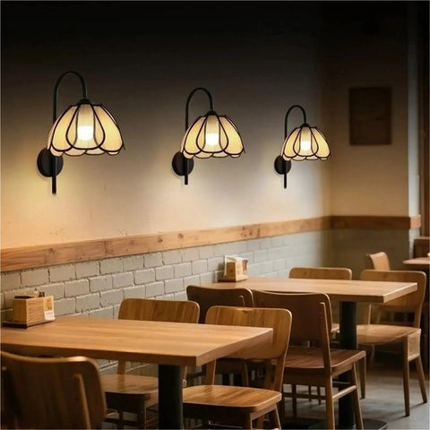 Nordic Floral Petal Wall Sconce Fabric Shade Wall Light,Warmth in a cozy cafe setting with three soft-lit wall sconces.