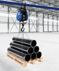 Huge 1100 Lb Electric Winch With Wireless Remote And 98 Foot Cable lifting black pipes from a wooden pallet in a warehouse.