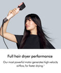 Woman using Coanda 2x Airwrap Multi Styler And Dryer For Straight And Wavy Hair In Ceramic Pink, showcasing high air power.