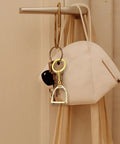 Elegant Stirrups and Snaffle Bit Key Rings D Shaped Keychain hanging on hook with mask and keys, made from sturdy alloy for equestrians.
