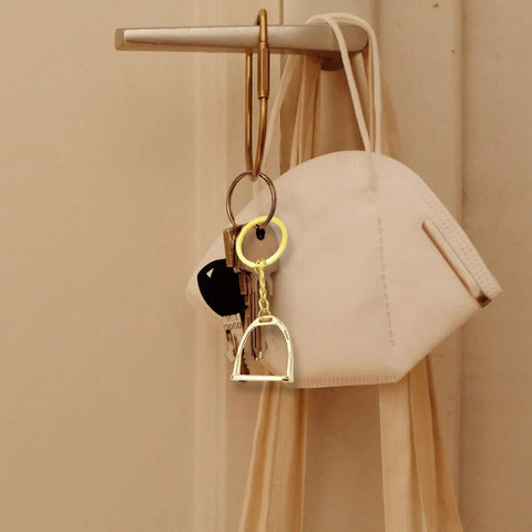 Elegant Stirrups and Snaffle Bit Key Rings D Shaped Keychain hanging on hook with mask and keys, made from sturdy alloy for equestrians.