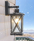 Two Pack Dusk To Dawn Outdoor Wall Lanterns With Photocell Sensor mounted on snowy porch, black aluminum with clear glass