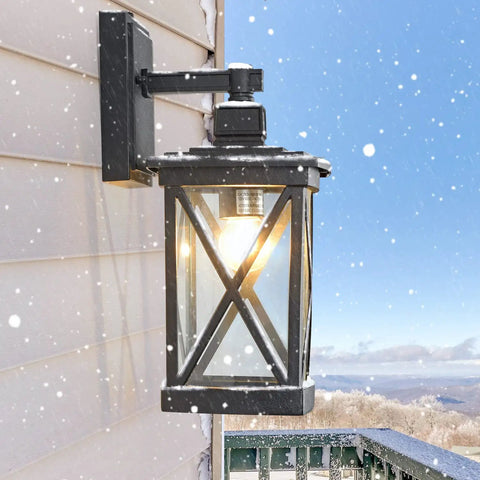 Two Pack Dusk To Dawn Outdoor Wall Lanterns With Photocell Sensor mounted on snowy porch, black aluminum with clear glass