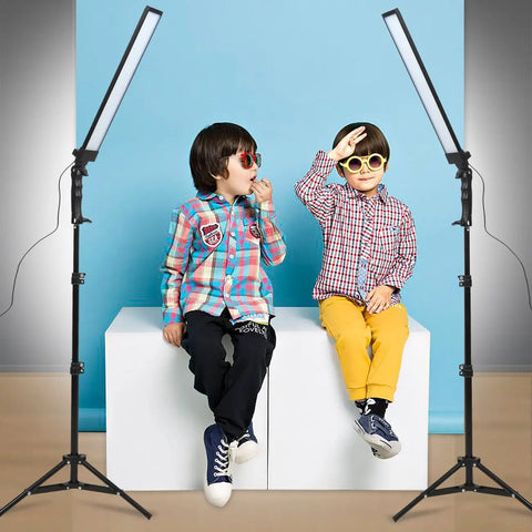 Children sit between the 180 LED Photography Studio Lighting Kit With Pro Grade Handheld Wand Light On Stand And Tripod Plus Bag For Photo And Video Filming