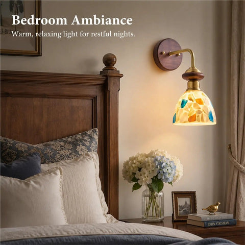 BZXNC Indoor Wall Sconce Lamp, Vintage 12.20" Copper, Compact Structure, glowing brass lamp with colorful glass shade above a bed.