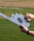Hands holding Spirit Of America Twin 30mm EDF RC Warbird BNF Basic airplane with safe select in outdoor field.