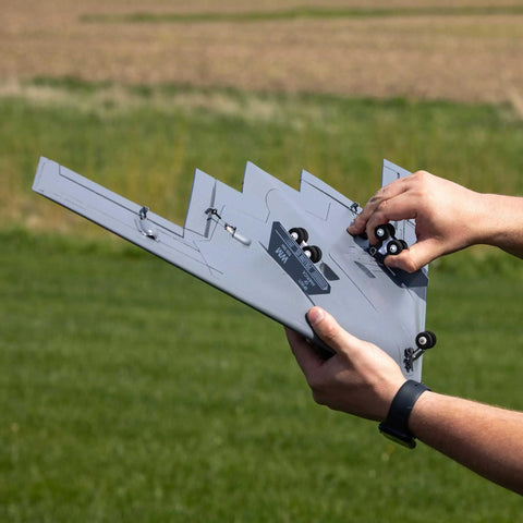 Hands holding Spirit Of America Twin 30mm EDF RC Warbird BNF Basic airplane with safe select in outdoor field.