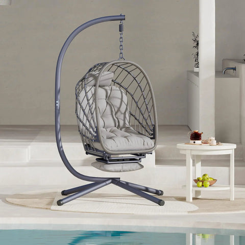 Cozy Outdoor Egg Swing Chair With Stand And Footrest Deep Cushioned Hammock Style Seat For Patio Or Indoor Use Waterproof Rattan Sturdy Metal Frame Comfy Lounge Chair In Dark Gray on a patio by a pool.