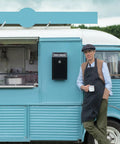 Man in apron next to food truck with Locking Cash Box With Slot For Donations, Metal Money Box, wall-mounted on blue vehicle.