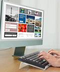 Person typing on a keyboard placed on a clear acrylic stand at 15° angle, part of the Two Pack Tilted Keyboard Stand In Clear Acrylic For Ergonomic Typing.