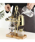 Top Shelf Siphon Coffee Maker Syphon Glass Brewer 4 Cup with gold accents and ergonomic handle, pouring water for brewing.