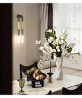Elegant U Shaped Horsehair Wall Lamp In Sleek Black Delivering Crisp Cool White Glow For Living Rooms And Hallways That Bring Dope Minimalist Vibes And Flicker Free Comfort next to vase and decor.